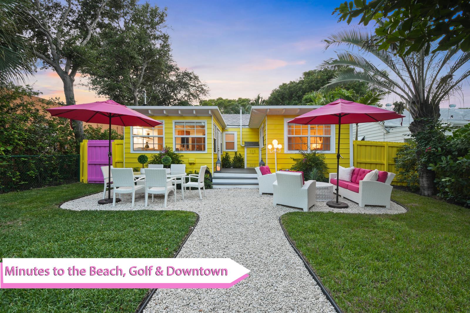 A yellow house with a gravel patio, outdoor furniture, and two pink umbrellas — 612 N Palmway, FL 33460, FL