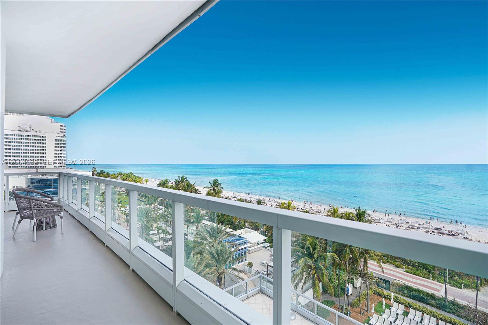 A balcony with a glass railing overlooks a beach and the ocean — 4391 Collins Ave # 709, Miami Beach FL 33140, MIAMI BEACH, FL