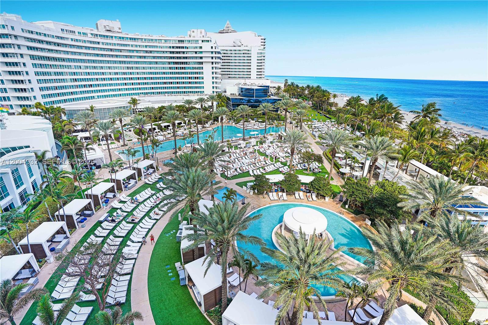 An aerial view shows a large resort hotel with multiple swimming pools and palm trees — 4391 Collins Ave # 709, Miami Beach FL 33140, MIAMI BEACH, FL