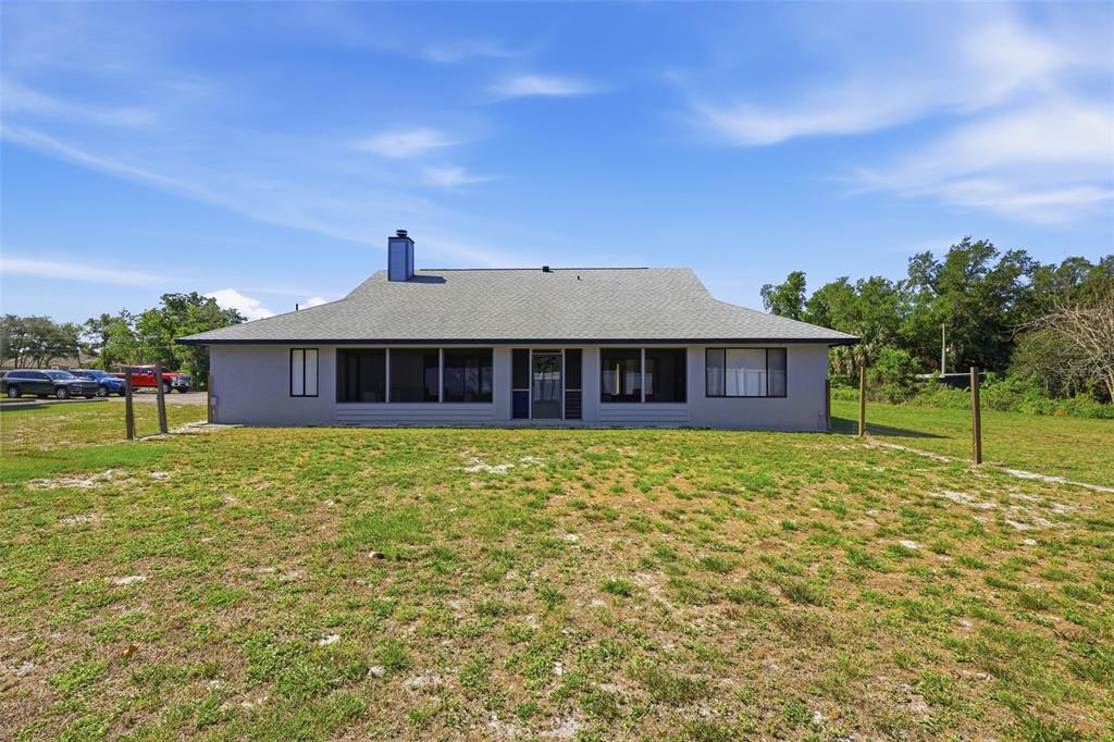 The rear exterior of a single-story house features a screened porch and a gray roof — 168 COMMUNITY DRIVE, DEBARY, FL