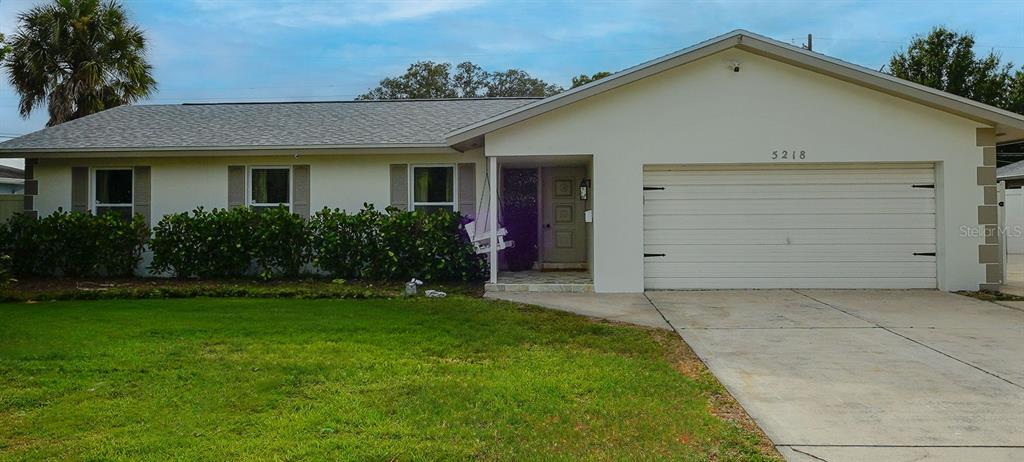 A single-story house with a light-colored exterior, a two-car garage, and a large front lawn — 5218 VENETIAN BOULEVARD NE, ST PETERSBURG, FL