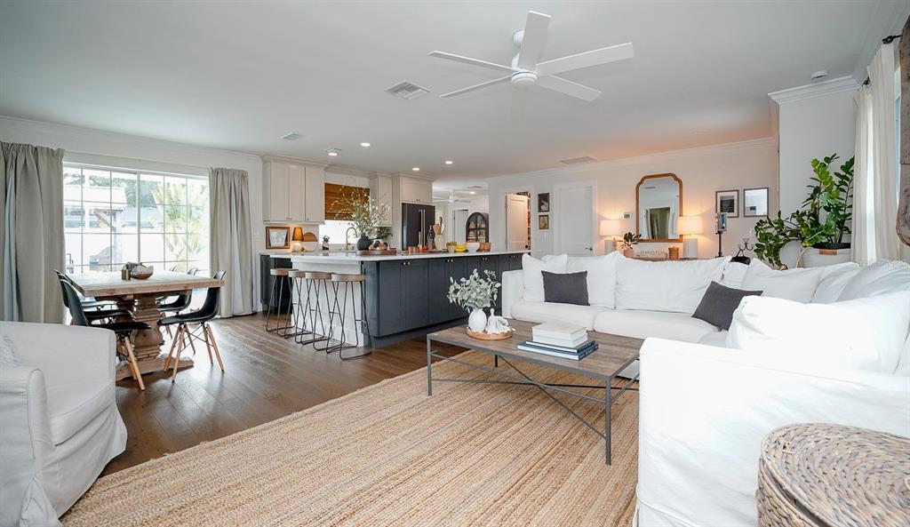 An open-concept living room and kitchen featuring white cabinetry, a dark island, and wood floors — 5218 VENETIAN BOULEVARD NE, ST PETERSBURG, FL