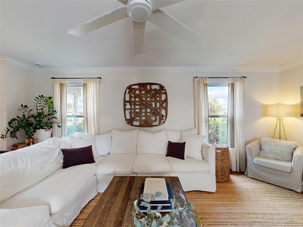 A living room features a white sectional sofa, a wooden coffee table, and two windows — 5218 VENETIAN BOULEVARD NE, ST PETERSBURG, FL