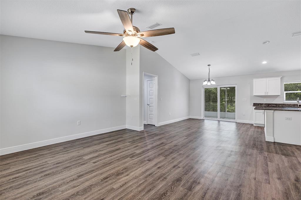 A spacious living area with wood-look flooring, a vaulted ceiling, and an open kitchen — 9219 N ELKCAM BOULEVARD, CITRUS SPRINGS, FL