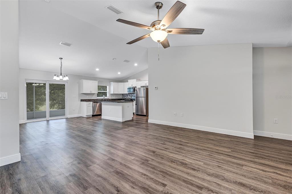 An open-concept living room and kitchen featuring wood-look flooring, white cabinetry, and a ceiling fan — 9219 N ELKCAM BOULEVARD, CITRUS SPRINGS, FL