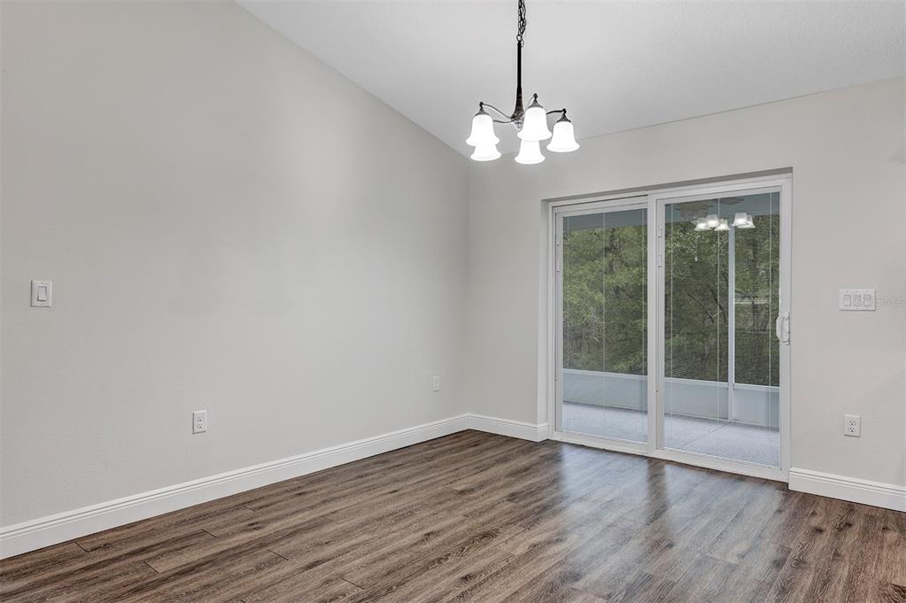 An empty dining room features wood-look flooring, a chandelier, and a sliding glass door — 9219 N ELKCAM BOULEVARD, CITRUS SPRINGS, FL