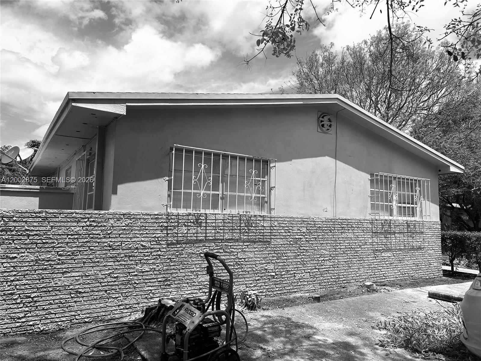 A single-story house exterior features a brick lower facade, stucco upper walls, and window security bars — 412 SW 10th St # 2, Hallandale Beach FL 33009, HALLANDALE BEACH, FL