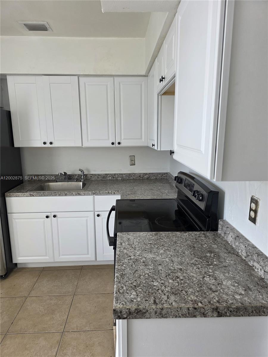A kitchen features white cabinets, granite countertops, a stainless steel sink, and black appliances — 412 SW 10th St # 2, Hallandale Beach FL 33009, HALLANDALE BEACH, FL