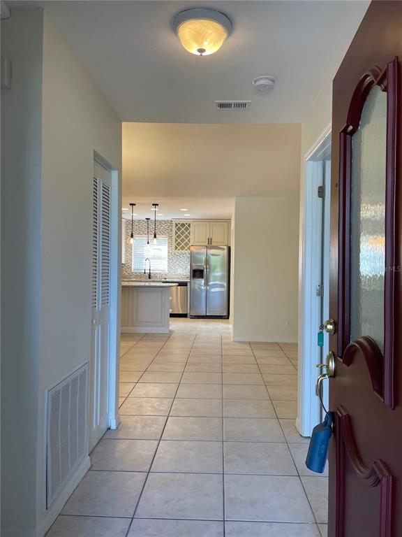 A view from an entryway looking toward a kitchen with tile floors and stainless appliances — 1424 CHESTERFIELD DRIVE, DUNEDIN, FL