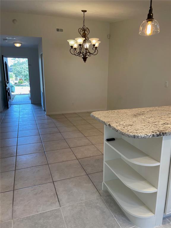 A kitchen island with granite countertops sits in a tiled room with a chandelier — 1424 CHESTERFIELD DRIVE, DUNEDIN, FL
