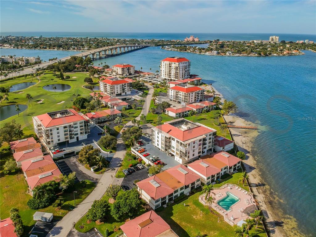 An aerial view shows a waterfront condominium complex with red-tiled roofs and a swimming pool — 6177 SUN BOULEVARD UNIT 606, ST PETERSBURG, FL