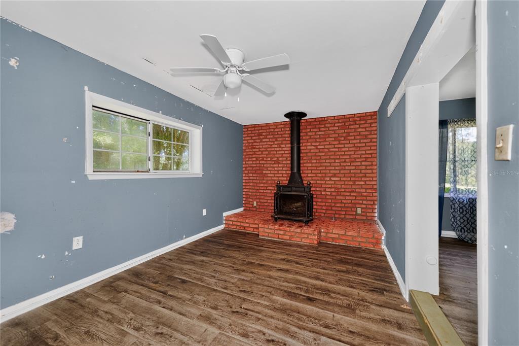 A room with blue walls, wood-look flooring, a ceiling fan, and a brick fireplace — 1510 MABRY STREET, TALLAHASSEE, FL