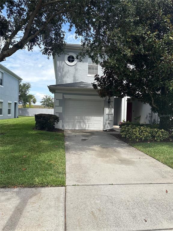 A two-story house with a single-car garage, a concrete driveway, and a small front lawn — 9428 FLOWERING COTTONWOOD ROAD UNIT 660, ORLANDO, FL