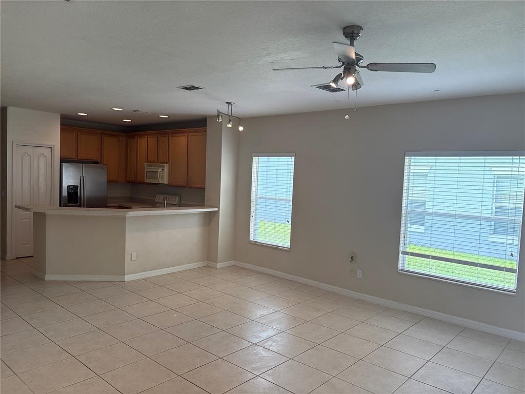 An open-concept kitchen with wood cabinets and tile flooring overlooks a spacious living area — 9428 FLOWERING COTTONWOOD ROAD UNIT 660, ORLANDO, FL