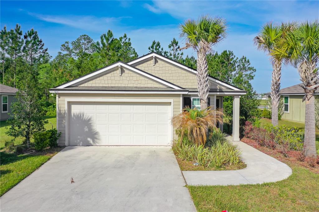 A single-story house with a beige exterior, a two-car garage, and two palm trees — 6214 WILD MUSTANG TRAIL, JACKSONVILLE, FL