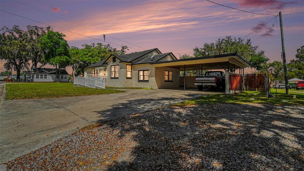 A single-story house with a carport, gravel driveway, and a white ramp at the entrance — 219 SW 6TH STREET, OCALA, FL