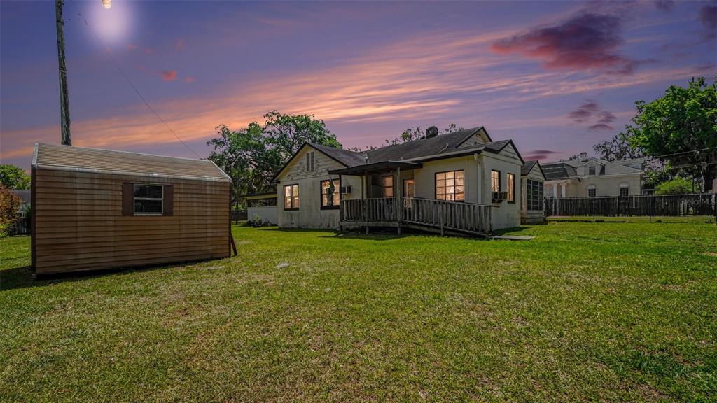 A backyard view of a single-story house with a wooden shed and a porch ramp — 219 SW 6TH STREET, OCALA, FL