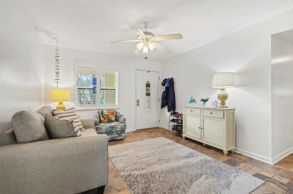 A living room features a gray sofa, patterned armchair, white cabinet, and tile flooring — 206 HARBOR DRIVE, CAPE CANAVERAL, FL