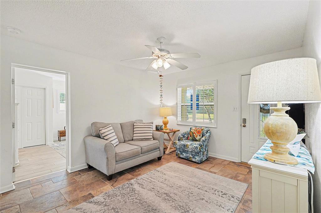 A living room features tile flooring, a gray loveseat, a patterned armchair, and a ceiling fan — 206 HARBOR DRIVE, CAPE CANAVERAL, FL