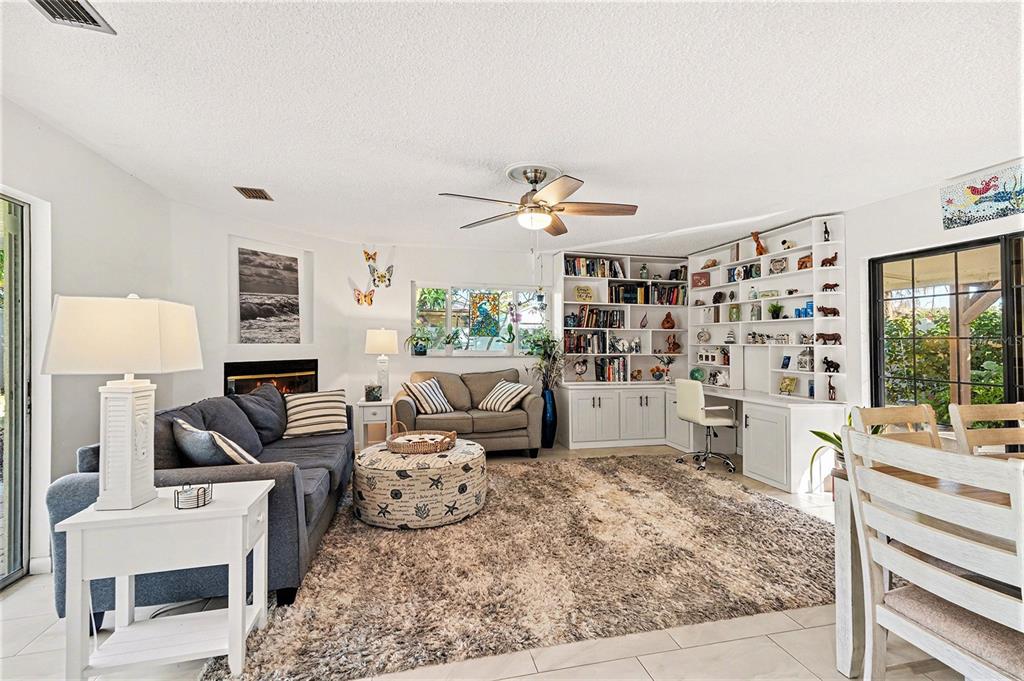 A living room features a fireplace, built-in shelving, a desk, and a large area rug — 206 HARBOR DRIVE, CAPE CANAVERAL, FL
