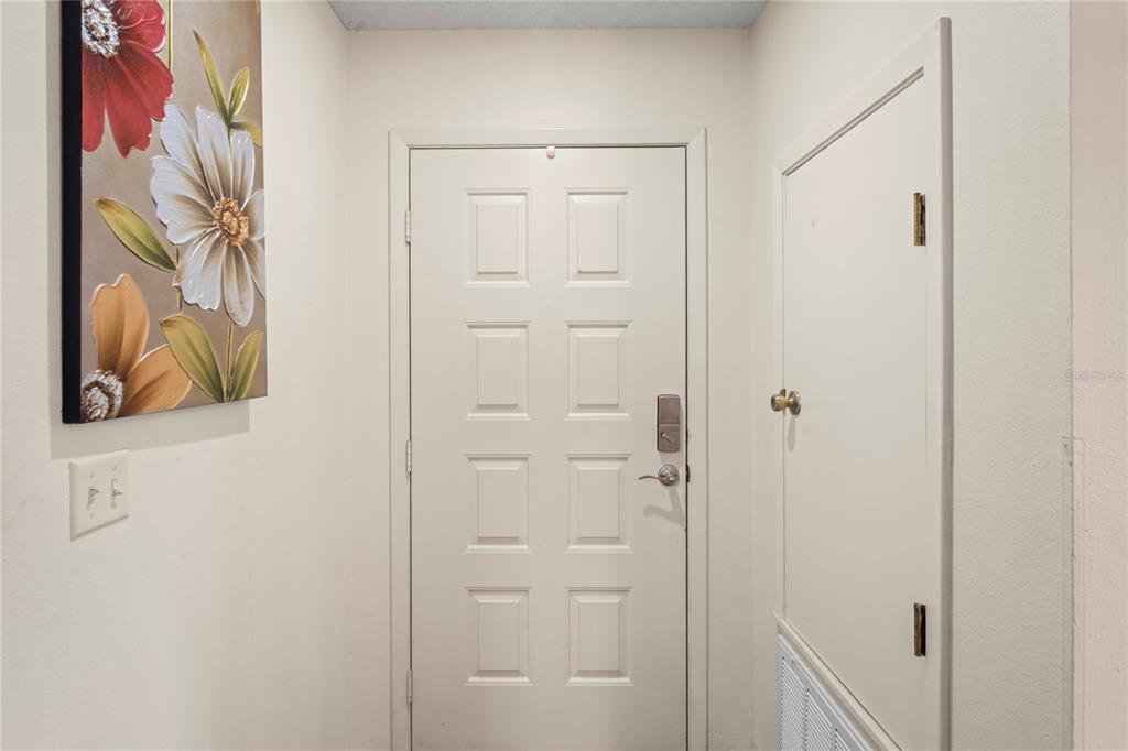 An interior entryway features a white door, a floral wall art piece, and a closet — 12041 HOOSIER COURT UNIT 202, HUDSON, FL