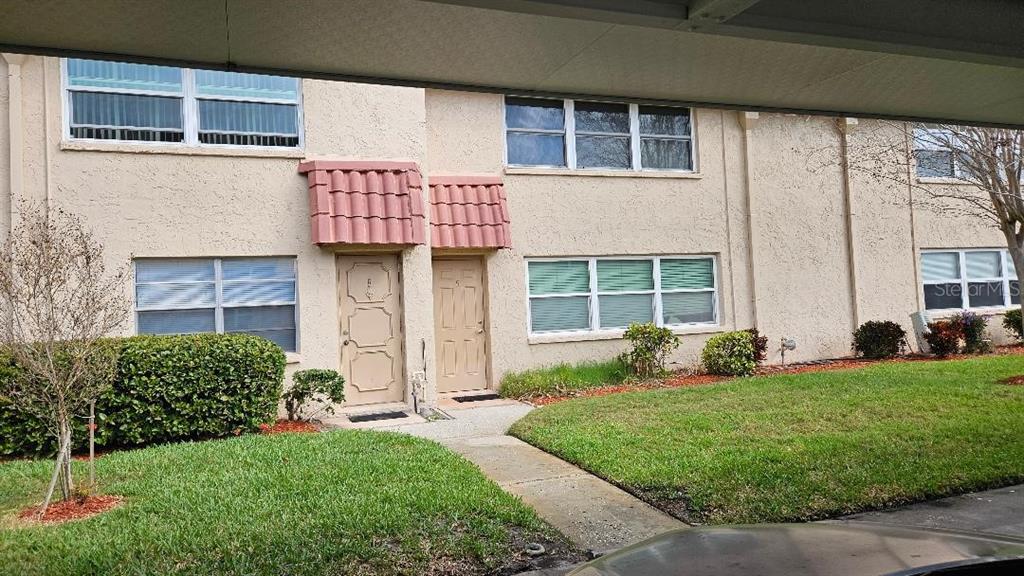 A two-story townhouse exterior features beige stucco walls, two front doors, and a covered walkway — 10035 63RD AVENUE N UNIT 6, ST PETERSBURG, FL