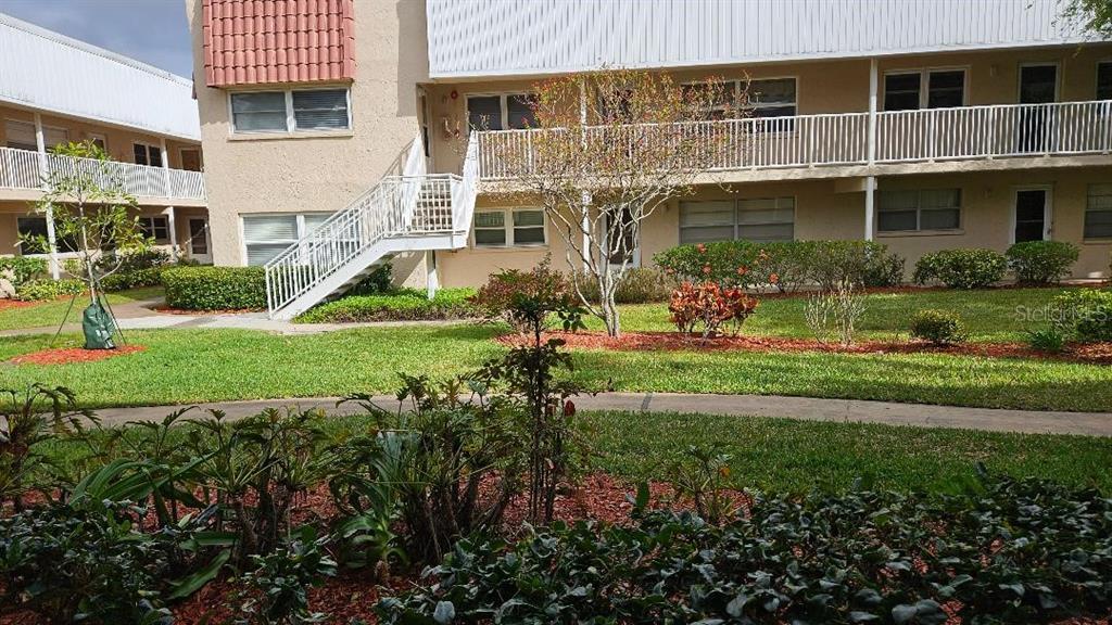 A multi-story apartment building with a white exterior, exterior staircases, and landscaped grounds — 10035 63RD AVENUE N UNIT 6, ST PETERSBURG, FL
