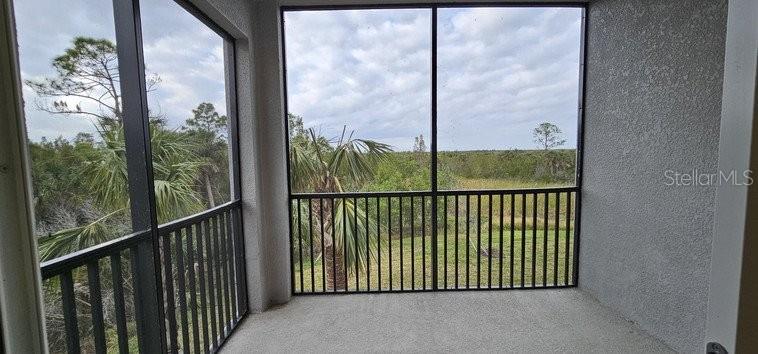 A screened-in balcony overlooks a grassy field and trees under a cloudy sky — 14161 HERITAGE LANDING BOULEVARD UNIT 1121, PUNTA GORDA, FL