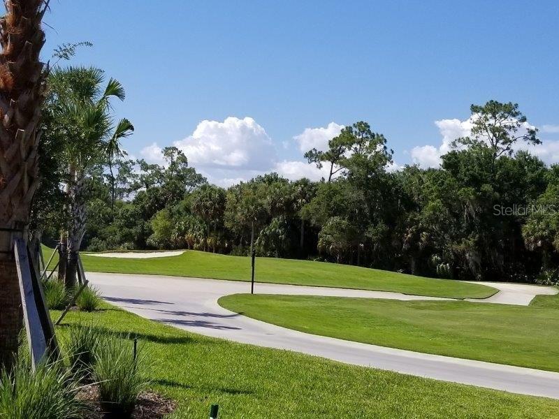 A paved path winds through a green golf course with a sand bunker and trees — 14161 HERITAGE LANDING BOULEVARD UNIT 1121, PUNTA GORDA, FL