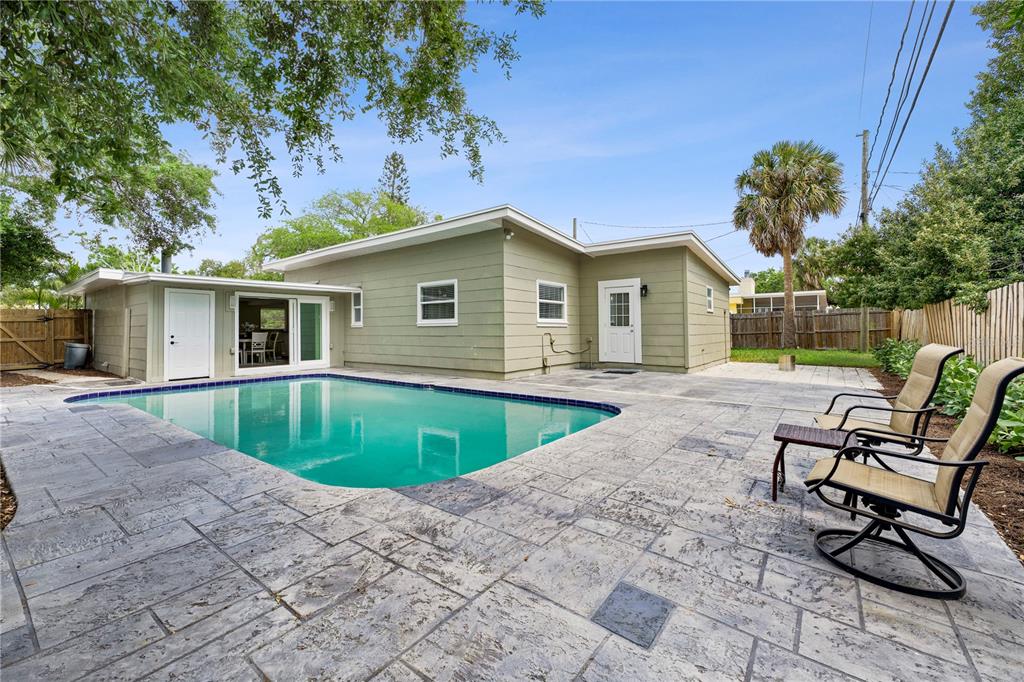 A backyard features a rectangular swimming pool surrounded by a stamped concrete patio — 7310 11TH AVENUE N, ST PETERSBURG, FL