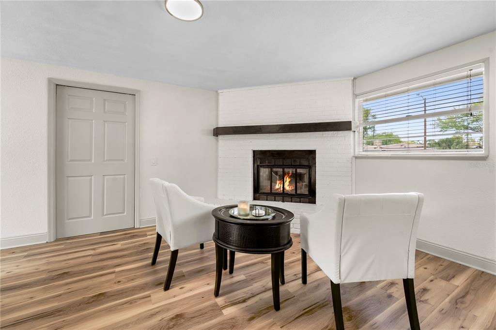 A room with wood-look flooring, a white brick fireplace, and two white chairs — 7310 11TH AVENUE N, ST PETERSBURG, FL