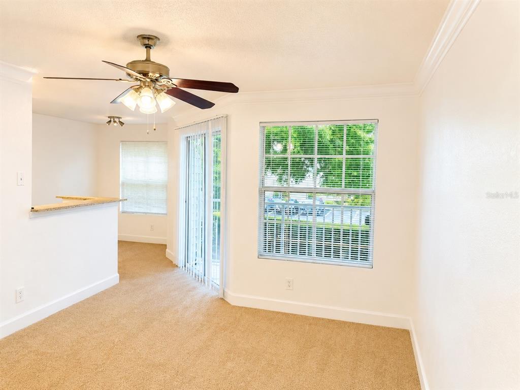 A carpeted living area features a ceiling fan, sliding glass doors, and a window — 11574 WESTWOOD BOULEVARD UNIT 1126, ORLANDO, FL