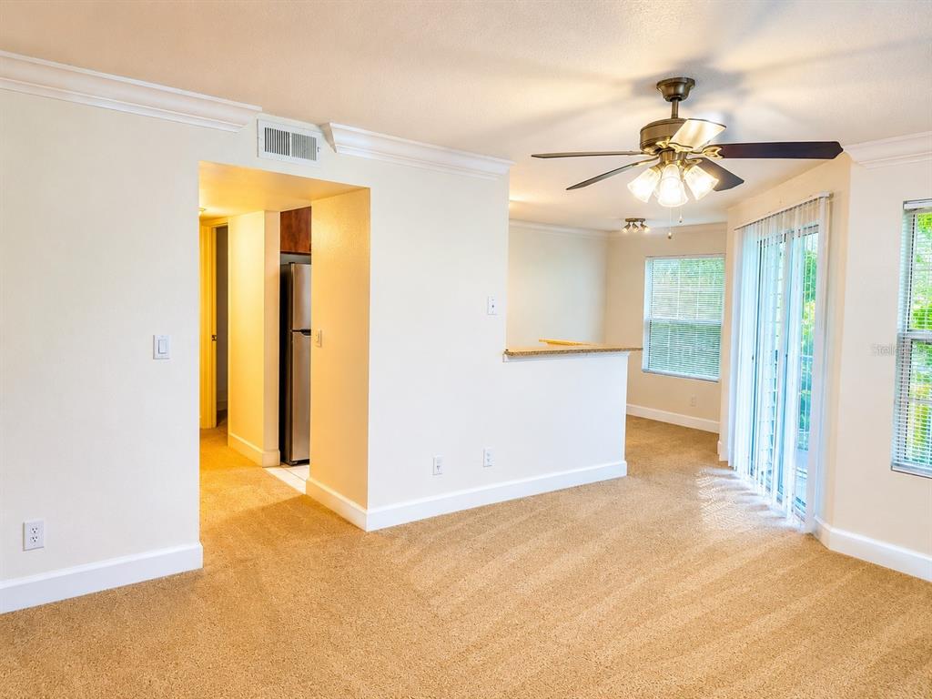 A carpeted living room features a ceiling fan, a kitchen pass-through, and sliding glass doors — 11574 WESTWOOD BOULEVARD UNIT 1126, ORLANDO, FL