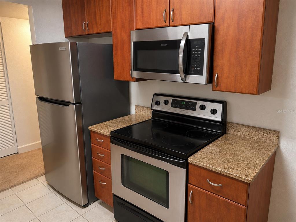 A kitchen features stainless steel appliances, wood cabinets, and speckled laminate countertops — 11574 WESTWOOD BOULEVARD UNIT 1126, ORLANDO, FL