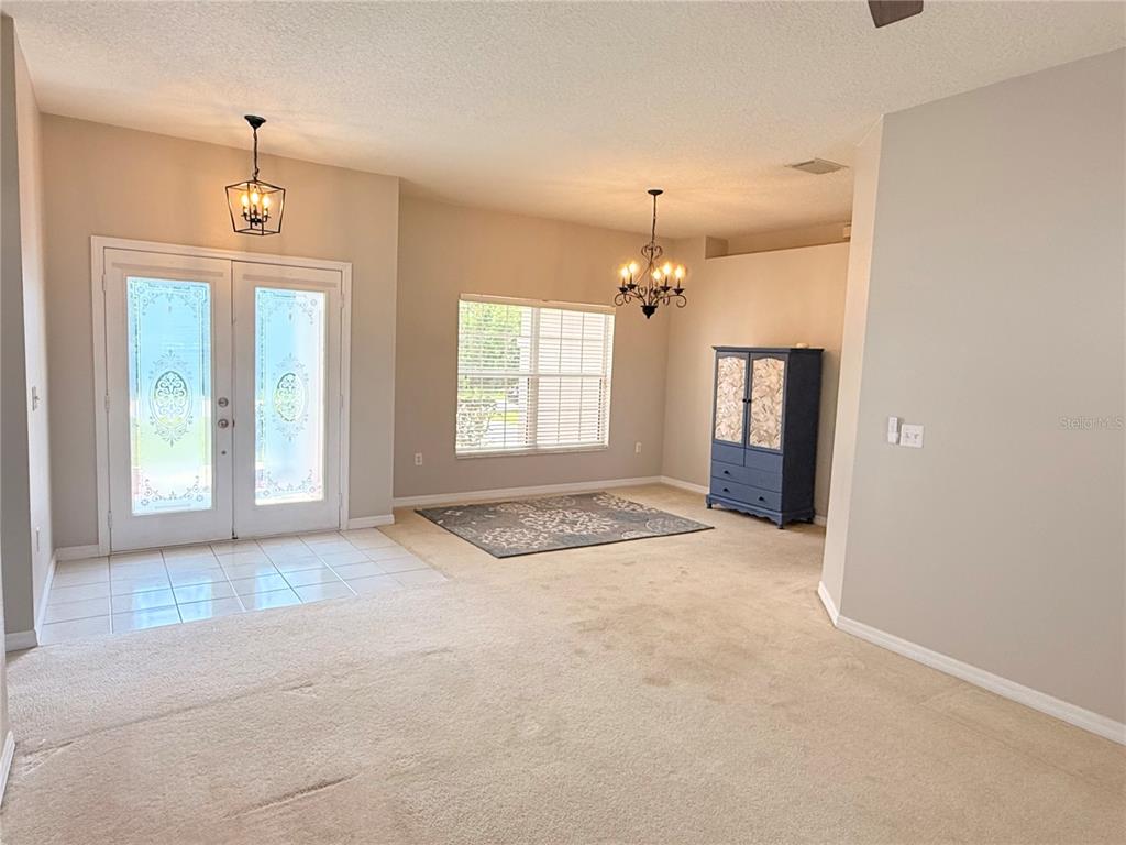 A living area with beige carpet, a tiled entryway, and a blue cabinet — 3010 VICTORIA DRIVE, KISSIMMEE, FL
