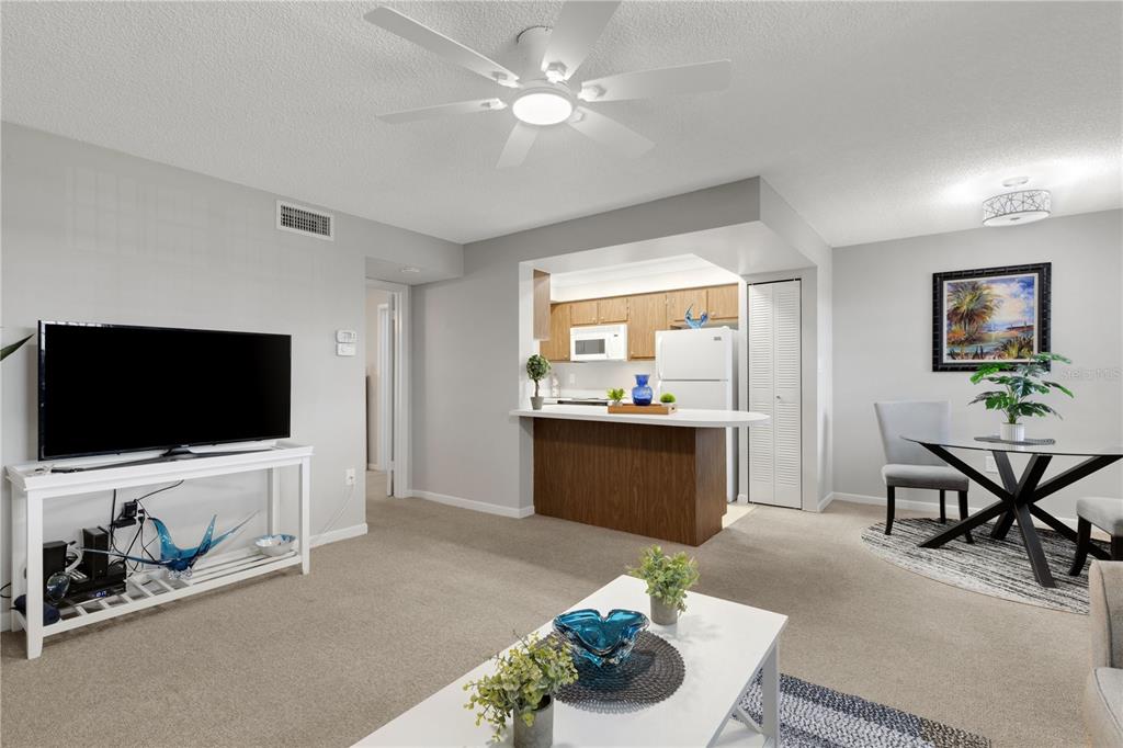 A living room with a ceiling fan, television, kitchen pass-through, and dining area — 105 47TH AVENUE DRIVE W UNIT 376, BRADENTON, FL
