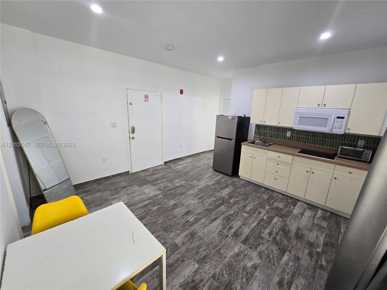 A kitchen with light-colored cabinets, stainless steel appliances, and wood-look flooring in an open room — 1345 Pennsylvania Ave # 5B, Miami Beach FL 33139, MIAMI BEACH, FL