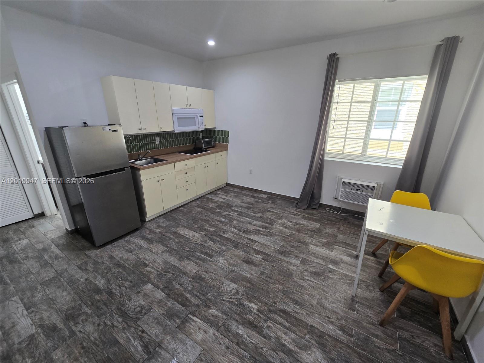 This kitchen features light-colored cabinetry, stainless steel appliances, and wood-look tile flooring — 1345 Pennsylvania Ave # 5B, Miami Beach FL 33139, MIAMI BEACH, FL