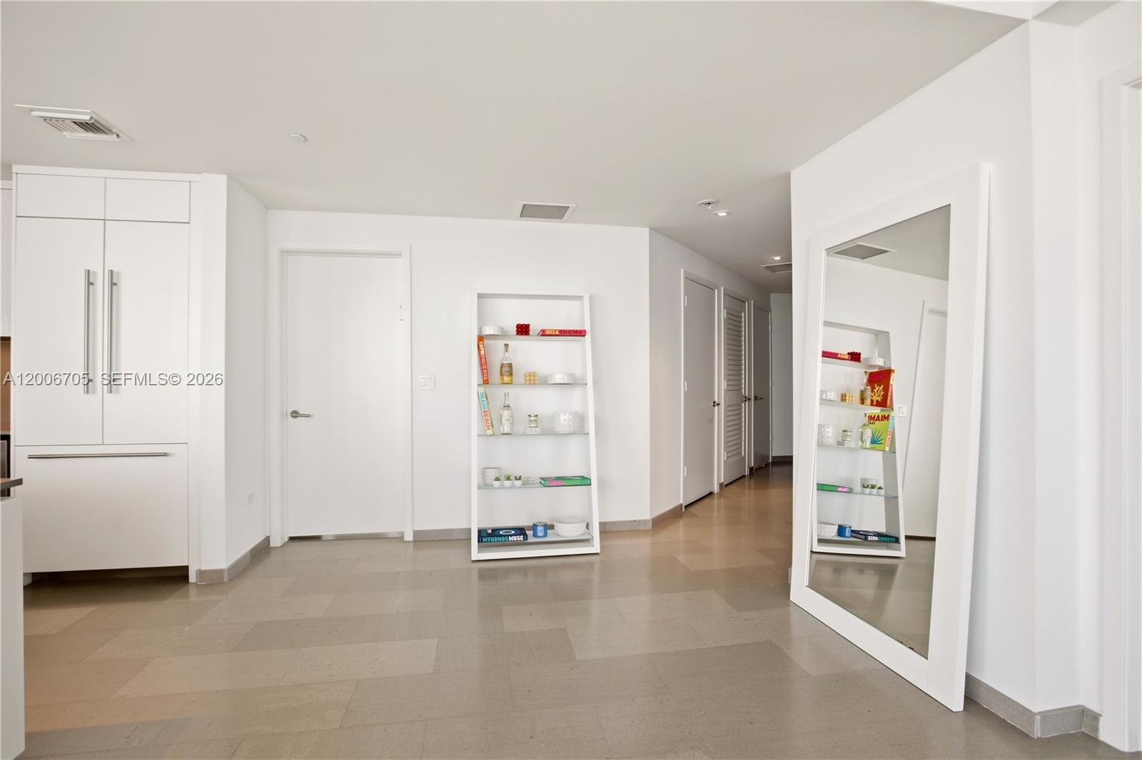 A minimalist hallway features white walls, light tile flooring, a shelving unit, and a large mirror — 68 SE 6th St # 2701, Miami FL 33131, MIAMI, FL