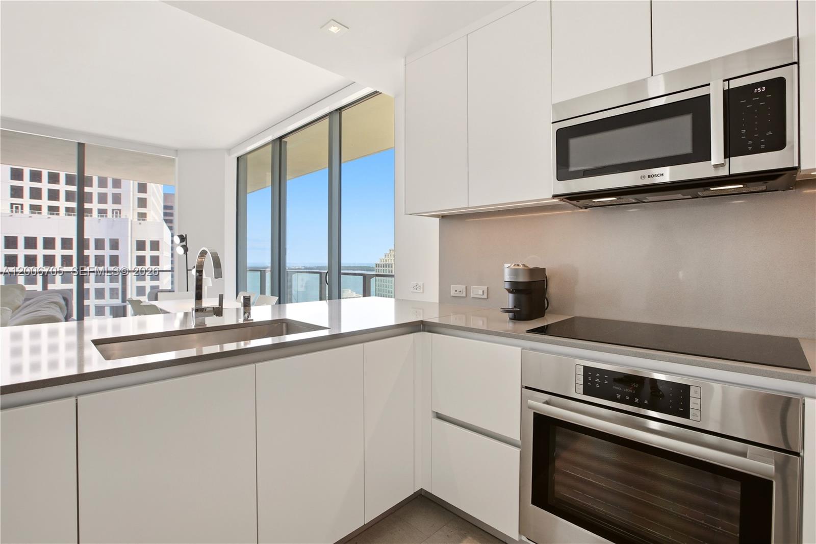 A modern kitchen features white cabinets, stainless steel appliances, and a view of the ocean — 68 SE 6th St # 2701, Miami FL 33131, MIAMI, FL