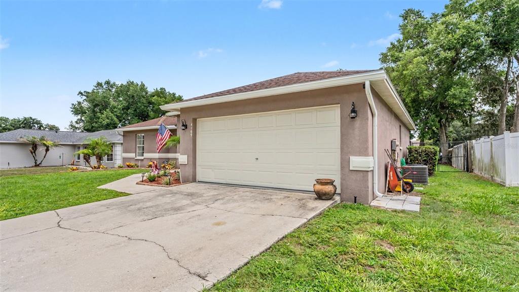 A beige house with a two-car garage, a concrete driveway, and a small American flag — 4169 MAYFAIR WAY, LAKELAND, FL