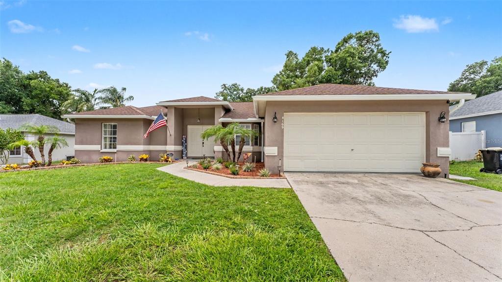 A single-story house with a beige stucco exterior, a two-car garage, and a front lawn — 4169 MAYFAIR WAY, LAKELAND, FL