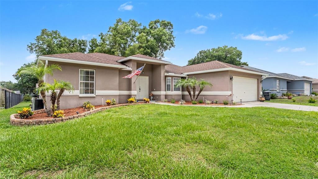 A single-story house with a tan stucco exterior, brown roof, and a front-facing garage — 4169 MAYFAIR WAY, LAKELAND, FL