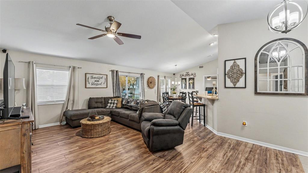 A living room features wood-look flooring, a sectional sofa, a recliner, and an open layout — 4169 MAYFAIR WAY, LAKELAND, FL