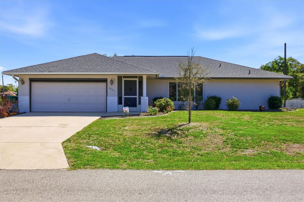 A single-story house with a gray roof, white stucco walls, and an attached two-car garage — 2084 LEISURE STREET, PORT CHARLOTTE, FL