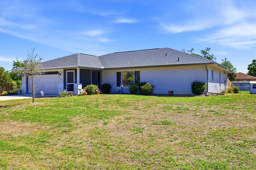 A single-story house with a gray roof, white stucco exterior, and an attached garage — 2084 LEISURE STREET, PORT CHARLOTTE, FL