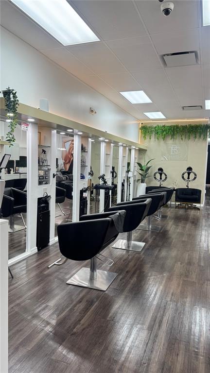 A hair salon interior features multiple black styling chairs, mirrors, and wood-look flooring — 13871 W HILLSBOROUGH AVENUE, TAMPA, FL