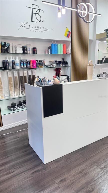 A salon reception area features a white desk, product shelving, and modern light fixtures — 13871 W HILLSBOROUGH AVENUE, TAMPA, FL