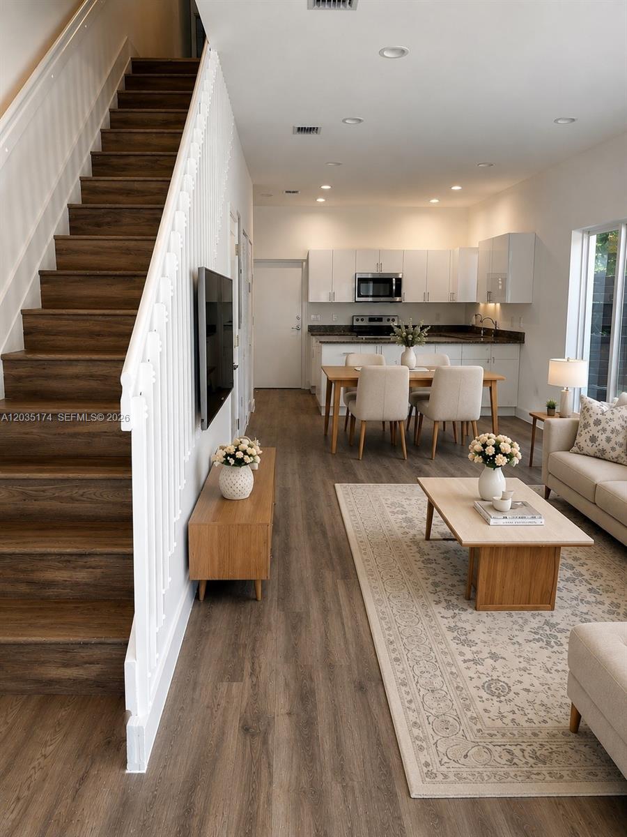 An open-concept living and dining area features wood-look flooring, a staircase, and a modern kitchen — 37 NW 70th St, Miami FL 33150, MIAMI, FL