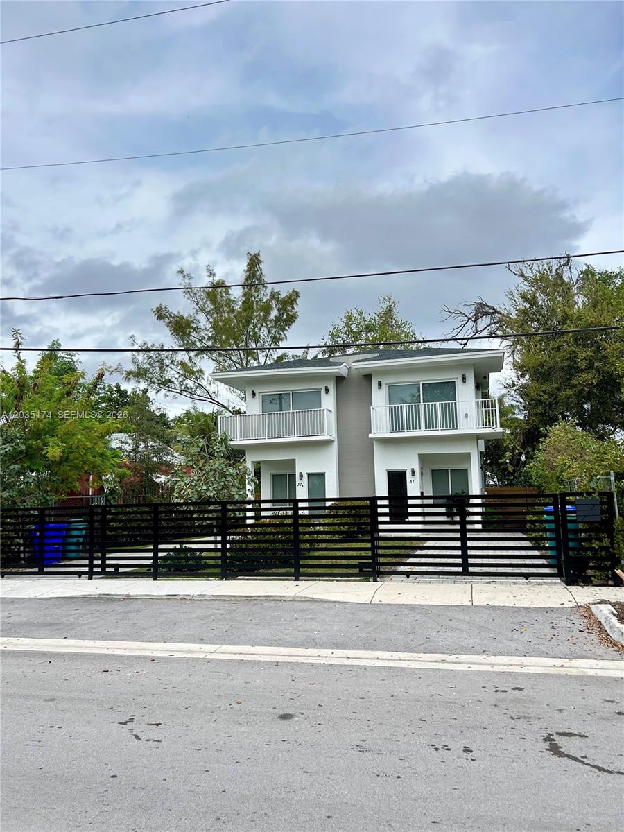A two-story duplex with white exterior walls, balconies, and a black horizontal slat fence — 37 NW 70th St, Miami FL 33150, MIAMI, FL
